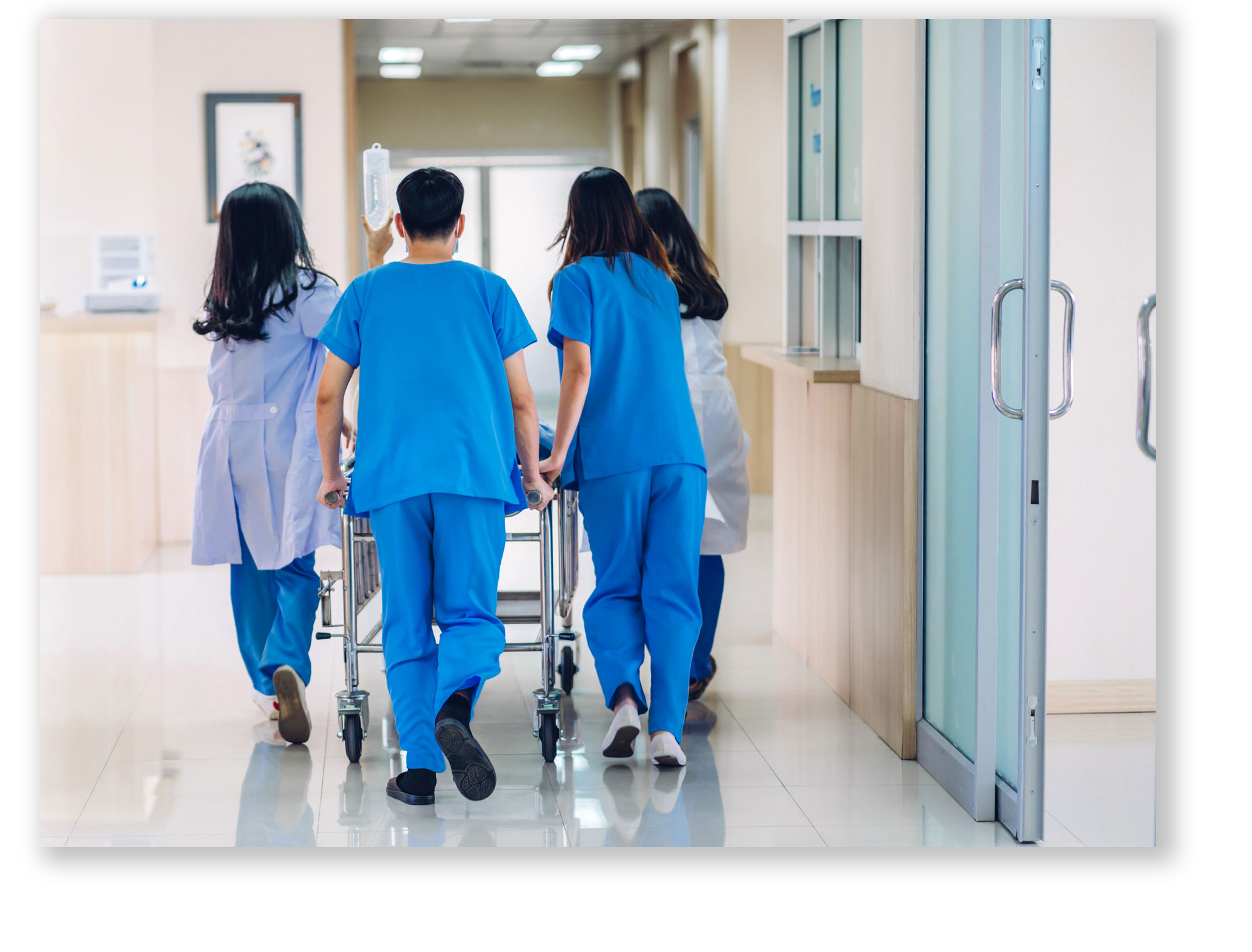 A group of doctors and nurses rushing a patient down a hospital ward corridor to surgery.
