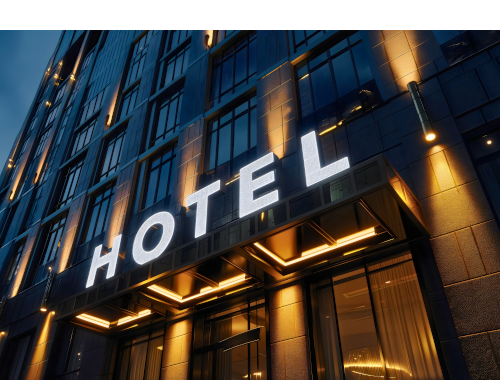 Beleuchtetes Hotelgebäude von außen am Abend mit Schriftzug Hotel