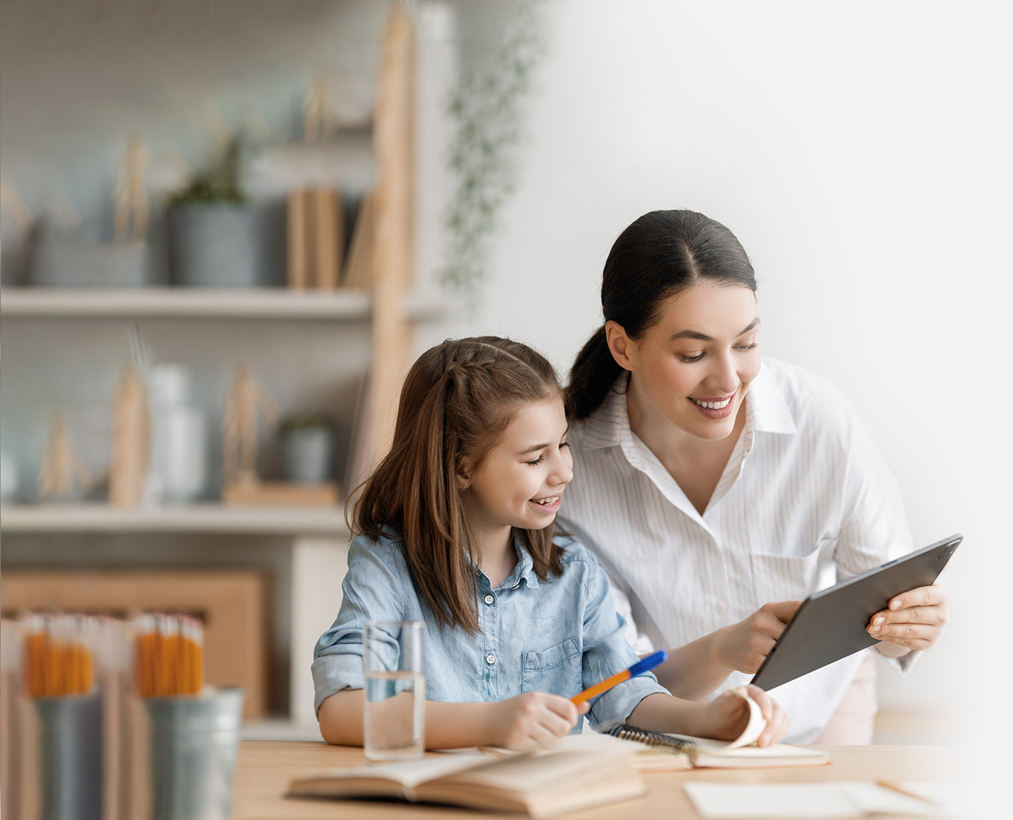 Mother using a tablet with parental controls and showing the screen to her daughter.