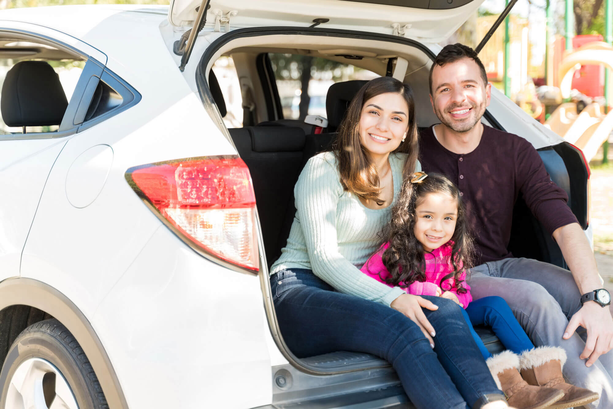 A smiling family sat in the boot of a car