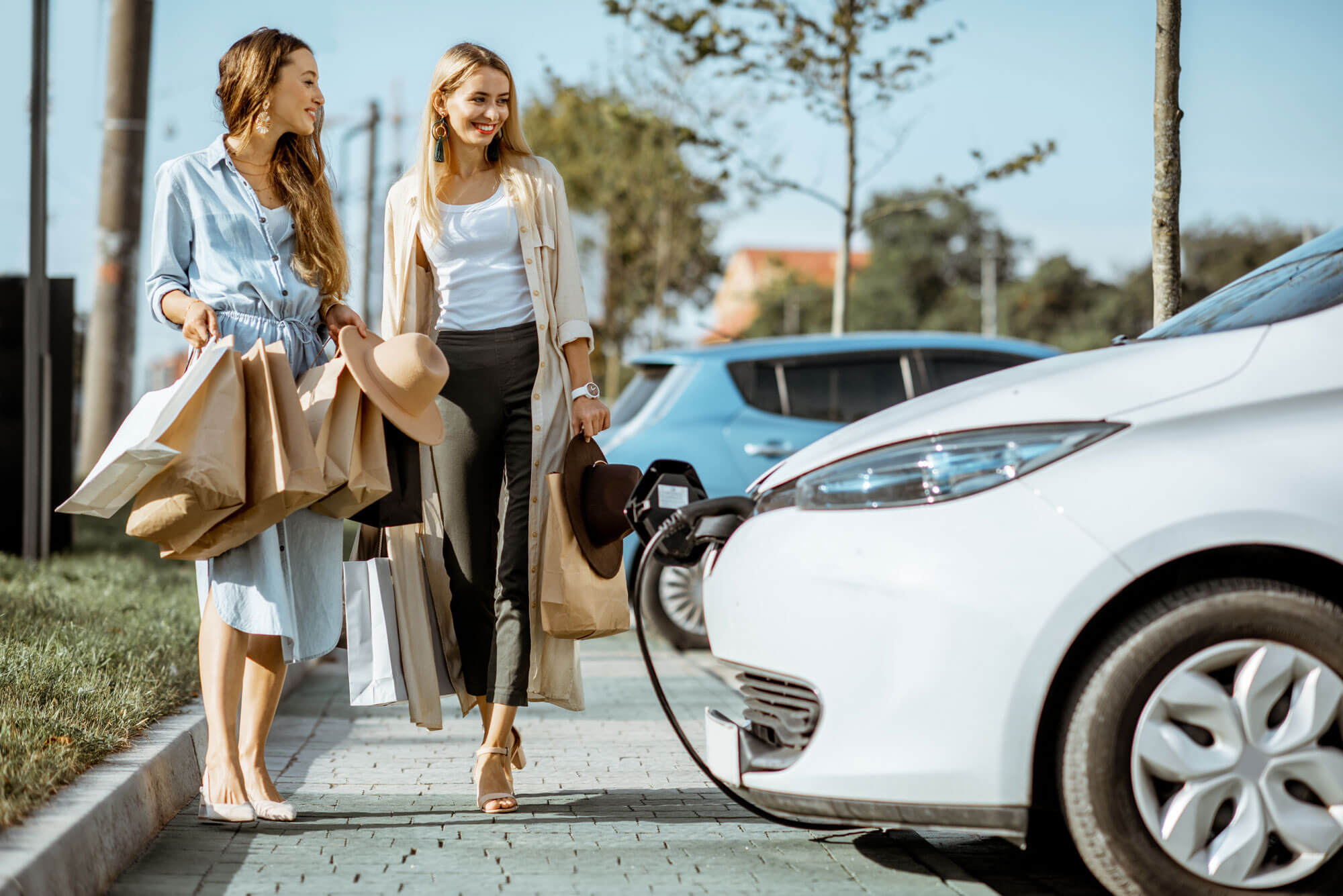 Shoppers looking at a charging car in a car park.