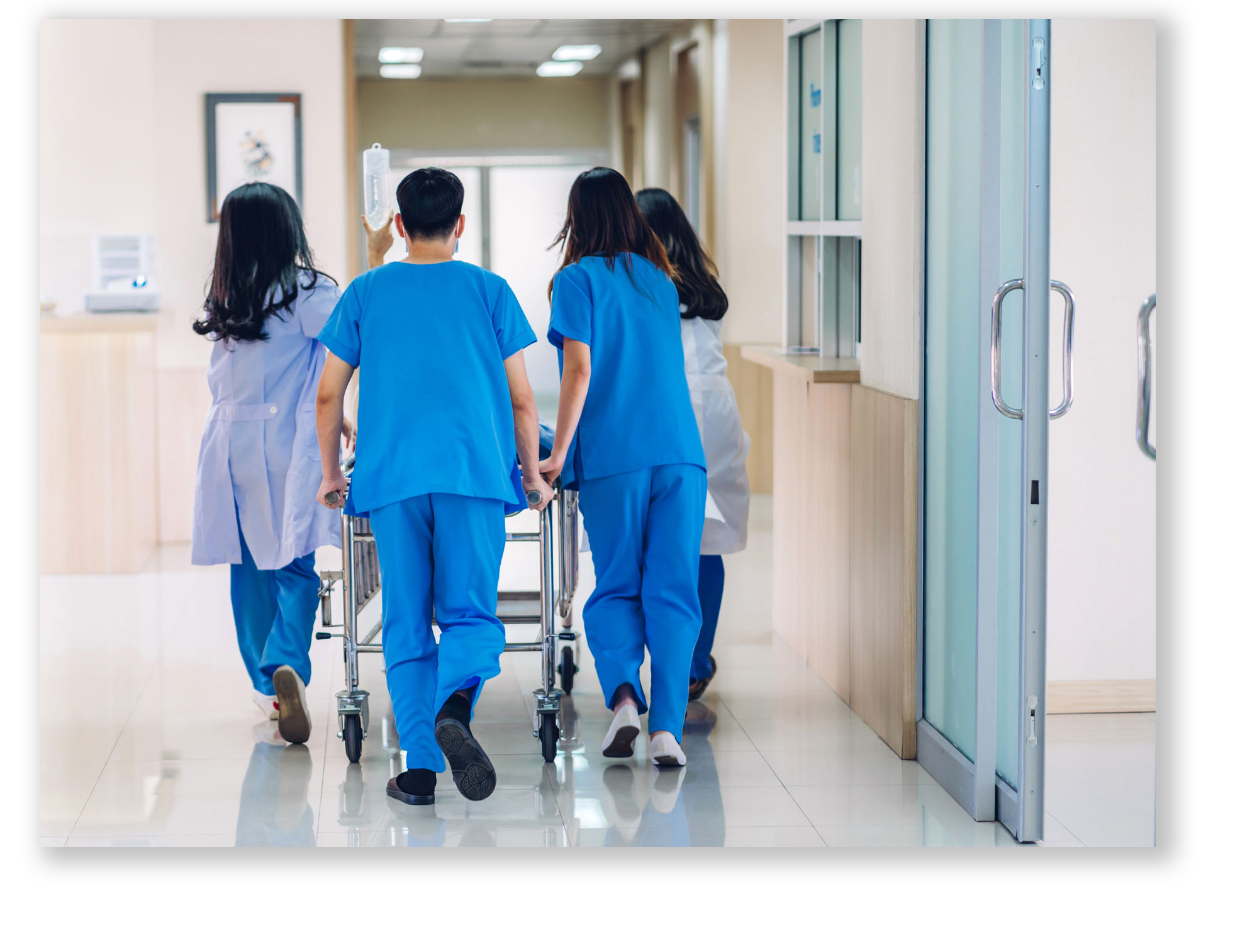 A group of doctors and nurses rushing a patient down a hospital ward corridor to surgery.